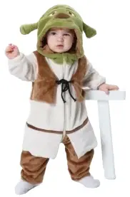 Dette billede viser et sjovt Shrek-kostume til børn, bestående af en beige overdel med påsyet vest, ternede bukser og en grøn maske med de karakteristiske troldeører. Dragten er designet i bløde materialer, der gør den behagelig for småbørn at have på til fastelavn eller leg.
