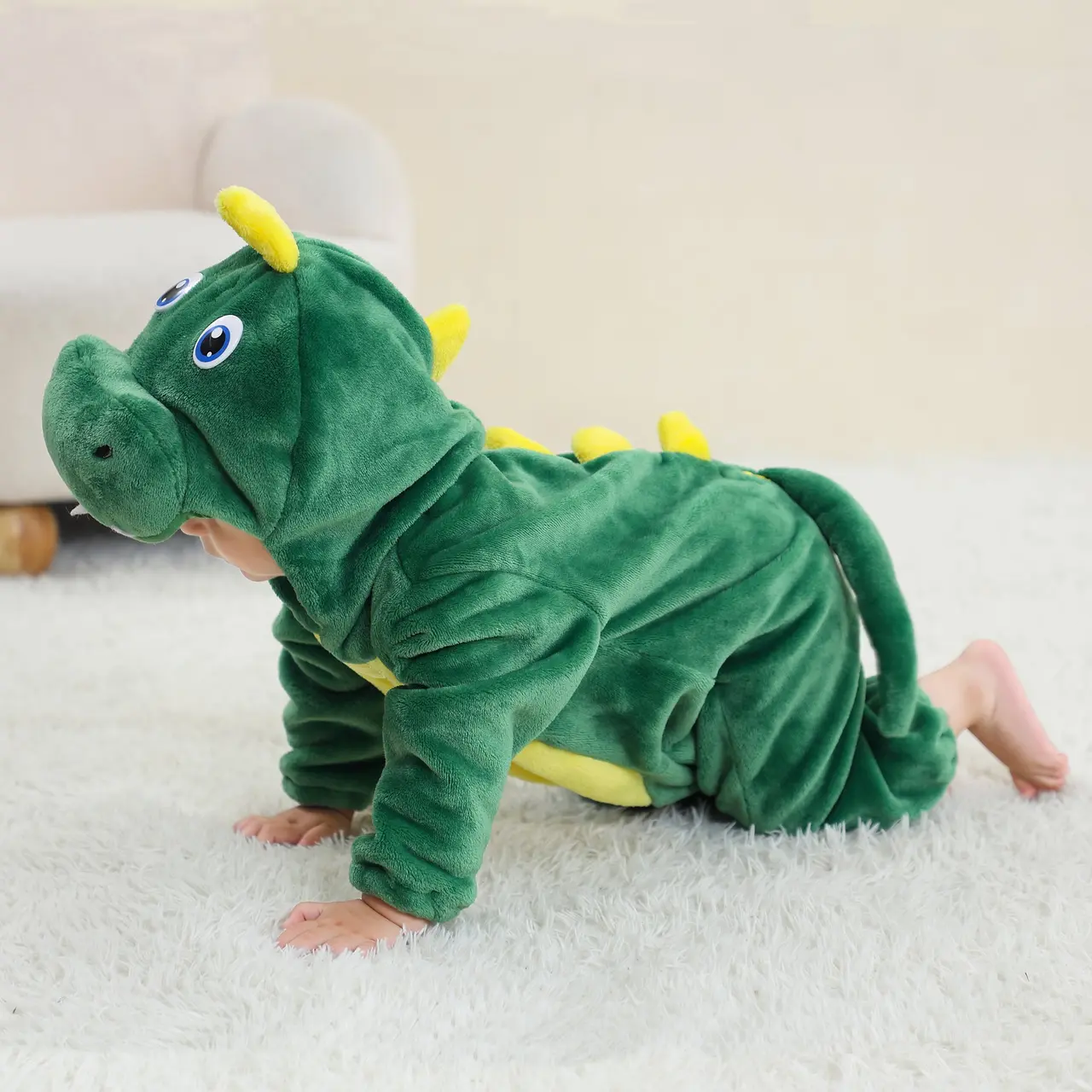 Et charmerende, grønt T-Rex kostume til børn lavet af blødt flannelmateriale. Dragten har en hvid mave, en række orange takker ned langs ryggen og en lang hale. Hætten er formet som et dinosaurhoved med store øjne og hvide tænder, hvilket gør det perfekt til både leg og fastelavn.