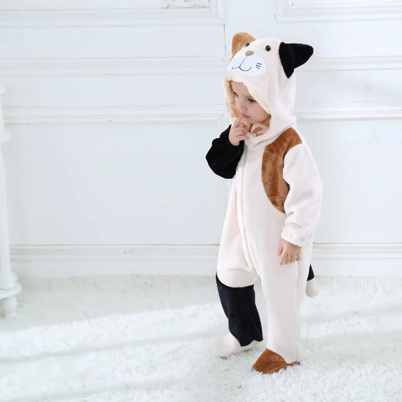Et blødt og behageligt beige kattekostume til småbørn, designet som en heldragt med en hvid mave. Dragten har en fastgjort hætte med søde katteører og en lille hale bagpå, hvilket gør den ideel til både leg og fastelavn.