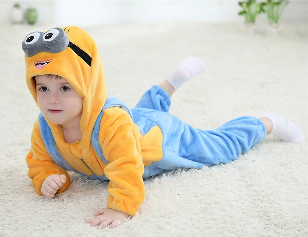 Et herligt Minion-kostume til børn, der består af en gul overdel og klassiske blå smækbukser med lomme. Dragten inkluderer en integreret gul hætte med karakteristiske briller og små hår på toppen, hvilket fuldender det sjove og genkendelige udseende fra filmene. Materialet ser blødt og behageligt ud, perfekt til leg og fastelavn.